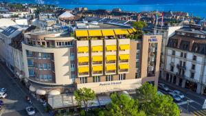 Studios Astra Hotel Vevey في فيفي: اطلالة علوية على مبنى ذو مظلات صفراء
