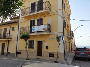 a yellow building with a car parked in front of it at Scilla Resort in Scilla