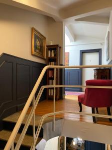a living room with a staircase and a red chair at LA VILLA Hôtel-Restaurant in Saverne