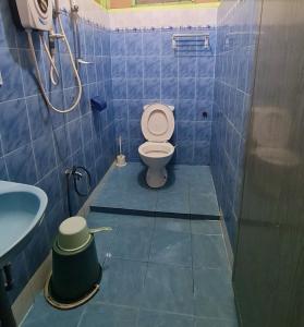 a blue tiled bathroom with a toilet and a sink at Rainbow Tioman Cottage in Kampong Juara