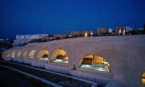 a building with a stone roof with windows at night at Divine Cave Experience in Imerovigli
