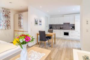 a living room and kitchen with a table and flowers in a vase at Haus Amber in Hödingen +19 photos