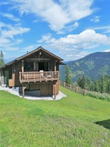 a log cabin with a deck and mountains in the background at Almresort Sommerschnee in Pruggern