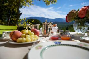 a table with a plate of fruit and a vase of roses at Schloss Englar in Appiano sulla Strada del Vino