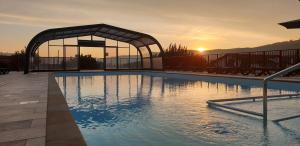 a large swimming pool with a sunset in the background at Domaine Chalets Larlapean in Saint-Martin-dʼArrossa