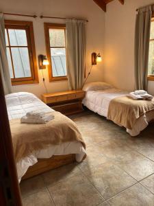 a bedroom with two beds and two windows at Refugio del Arroyo in San Martín de los Andes