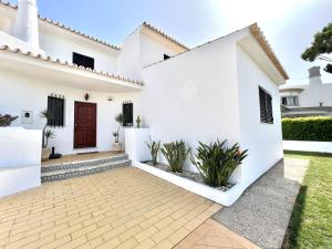 una casa bianca con una porta rossa e alcune piante di Duas Sentinelas - Private Pool by HD PROPERTIES a Quarteira