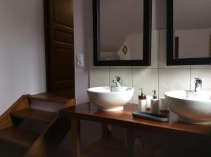 La salle de bains est pourvue de 2 lavabos blancs sur un comptoir en bois. dans l'établissement La Bergerie, à Gurs