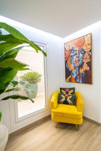 a yellow chair sitting in front of a painting on a wall at Hostal Romerito in Málaga