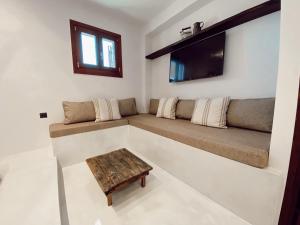a living room with a couch and a tv at Archo Suites Pythagoreio in Pythagoreio