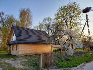 een klein huis met een zwart dak en een bord bij Dom z bali Chata Anna Bialowieza i okolice in Orla