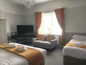1 dormitorio con 2 camas, silla y TV en The Black Lion Royal Hotel en Lampeter