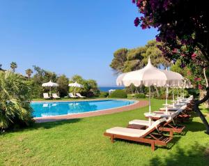 a row of lounge chairs and umbrellas next to a swimming pool at Hotel Cala Caterina in Villasimius