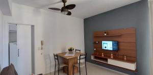 a dining room with a table and a tv on a wall at Apartamento com varanda - Sahy in Mangaratiba