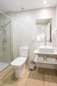 a white toilet sitting in a bathroom next to a sink at Hostal Romerito in Málaga