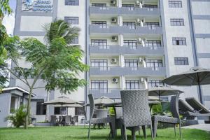 a hotel with tables and chairs in front of a building at Hotel Comster Mtwapa in Mtwapa