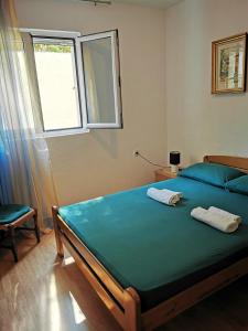 a bedroom with a bed with blue sheets and a window at Apartments Vila Andja in Sveti Stefan