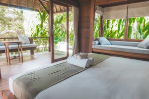 a bedroom with a large bed in a room with windows at Guava Garden in Gili Trawangan