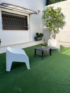 a patio with two white chairs and a table on green carpet at Casa De Curtis in Trecase