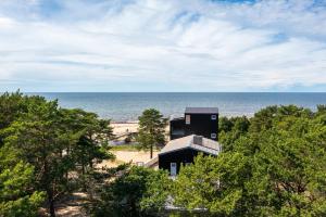 a building on the beach with the ocean in the background at Jõesuu Guesthouse in Vääna-Jõesuu