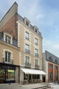 un grand bâtiment avec des tables devant lui dans l'établissement Le Nemours - Appartements Parcheminerie, à Rennes