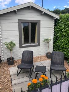 2 Stühle und Blumen auf einer Terrasse mit einem Haus in der Unterkunft Nancy's Cabin in Mosborough