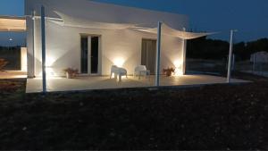 a white house with a table and chairs on a patio at Villetta vicino al mare in Porto Palo