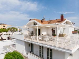 a white house with a balcony with white chairs at BeYou Hotel Villa Rosa in Riccione