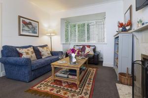 a living room with a blue couch and a table at 4 Bed - Beach Cottage in Torquay