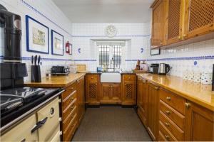 a kitchen with wooden cabinets and a clock on the wall at 4 Bed - Beach Cottage in Torquay