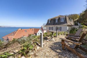 une maison assise au sommet d'une colline à côté de l'océan dans l'établissement 5 Bed - Foxes Walk, à Torquay