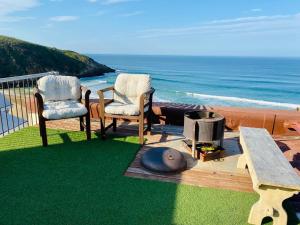 two chairs and a fire pit on a deck with the ocean at Top beach studio in Herolds Bay