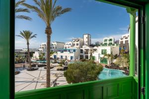 a window view of a city with palm trees and a pool at Hotel LIVVO Volcán Lanzarote in Playa Blanca