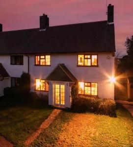 una casa blanca con sus luces encendidas por la noche en The Captain's Cottage at Climping en Climping