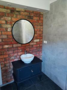 a bathroom with a sink and a mirror on a brick wall at Warmińska Przystań - dom całoroczny in Blanki