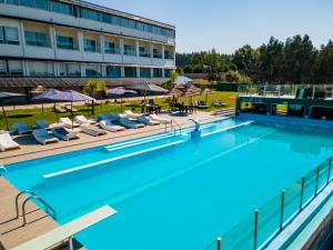 a pool at a hotel with chairs and umbrellas at Lisotel - Hotel & Spa in Leiria