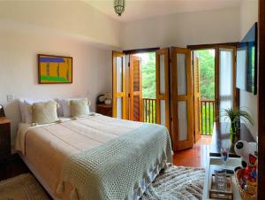 a bedroom with a bed and a balcony at Pousada Hortelã in Campos do Jordão