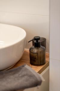 a bottle of soap sitting on a counter next to a sink at Apartamenty Termalne Dobry Klimat in Uniejow +55 photos