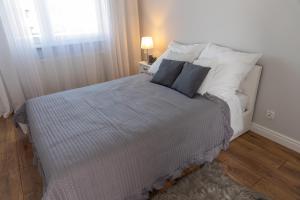 a bedroom with a bed with pillows and a window at Apartamenty Termalne Dobry Klimat in Uniejow