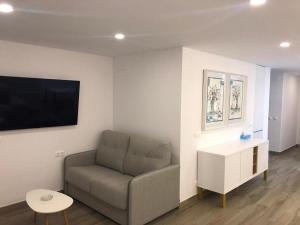 uma sala de estar com um sofá e uma televisão de ecrã plano em The luxury suite em Alicante