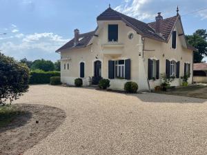 uma casa branca com janelas pretas e uma entrada em Chambres d´hotes VILLA CAPSYLVAINE em Captieux