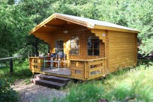 a wooden cabin with a deck in the grass at Hótel Eyvindará in Egilsstadir
