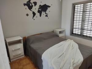 1 dormitorio con 1 cama y un mapa mundial en la pared en CASA MUY COMODA A METROS DEL SANTUARIO Y ECOPARQUE en San Nicolás de los Arroyos