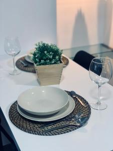 einen Tisch mit Tellern und Gläsern und eine Pflanze darauf in der Unterkunft Bodegas de Felicidad in Setenil de las Bodegas