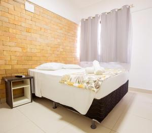 a bed in a room with a brick wall at Rede Andrade Ondina Salvador in Salvador