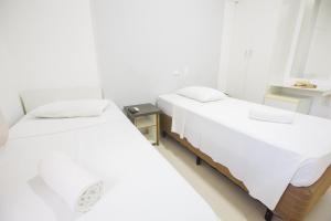 two beds in a room with white walls at Rede Andrade Ondina Salvador in Salvador