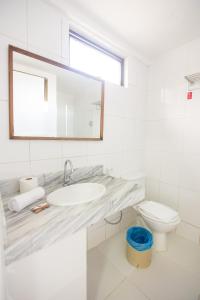 a white bathroom with a sink and a toilet at Rede Andrade Ondina Salvador in Salvador