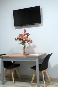 a table with a vase of flowers and a tv on a wall at Apartamentos Las trece llaves Jacuzzi bajo reserva in Mérida
