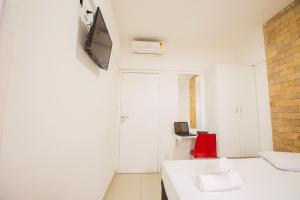 um quarto com uma cama branca e uma cadeira vermelha em Rede Andrade Ondina Salvador em Salvador