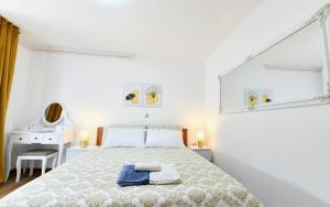 a white bedroom with a bed and a desk at Apartmani Brium in Rakovica